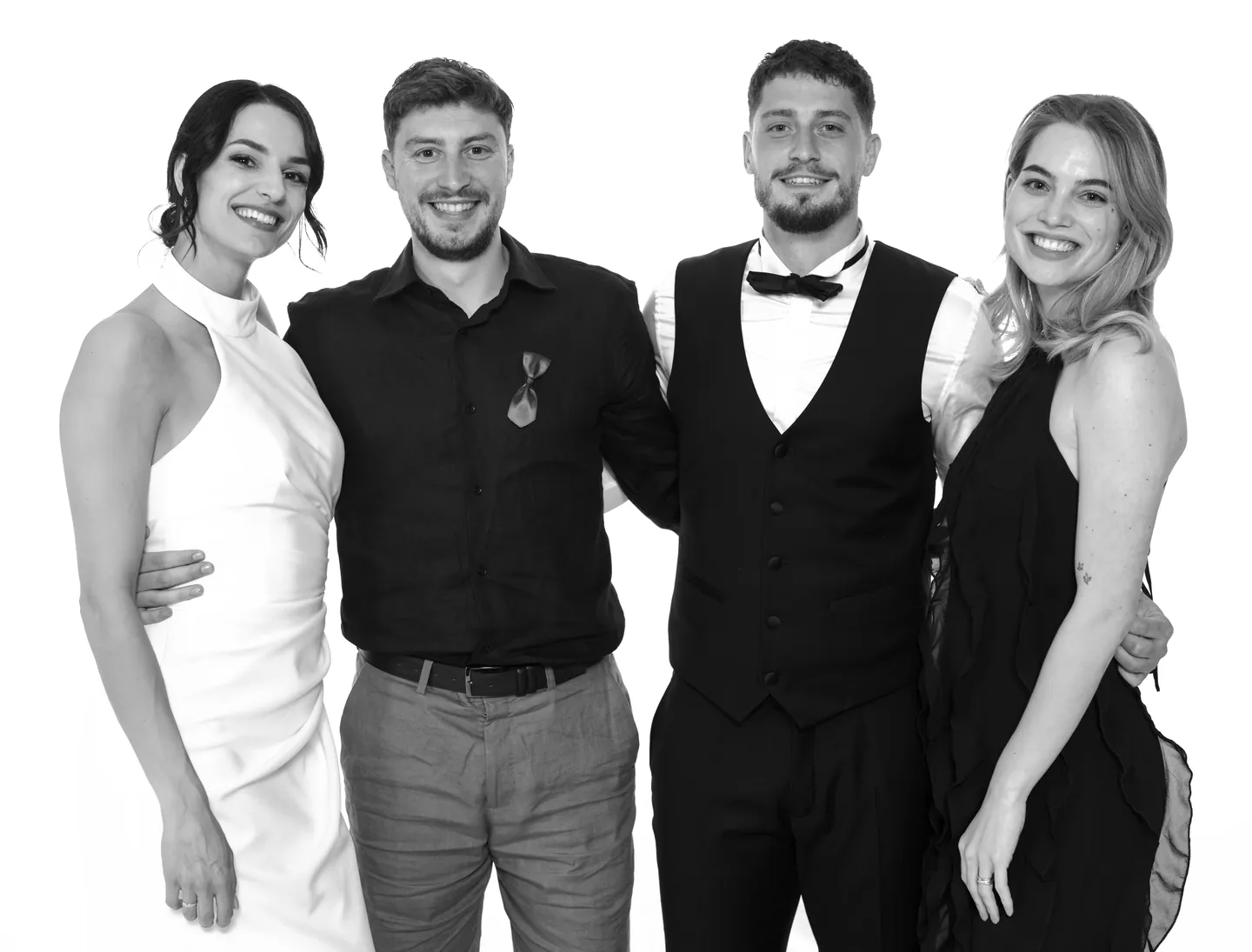 Dva para u elegantnoj odjeći smiju se ispred bijele pozadine
